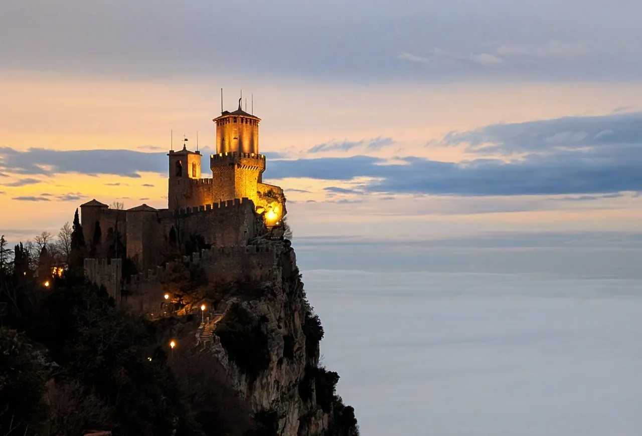 La torre Guaita sul Monte Titano al tramonto, sopra un mare di nuvole